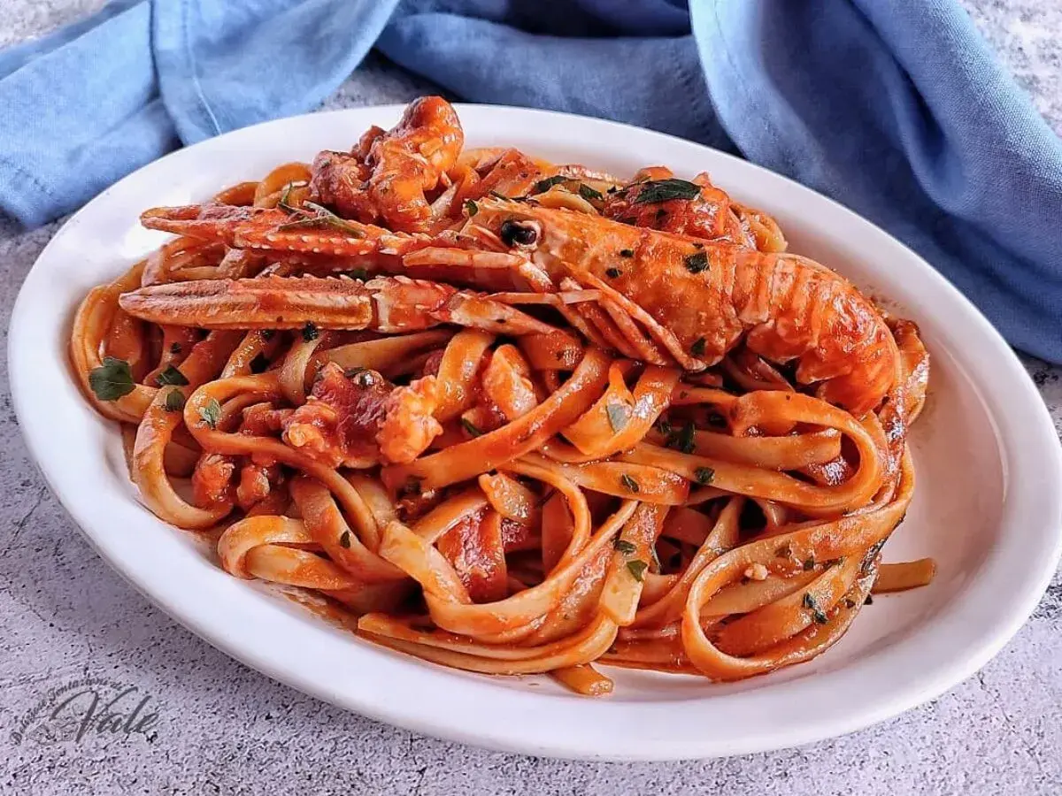 Un piatto invitante di linguine agli scampi, condite con un sugo rosso e guarnite con prezzemolo fresco.