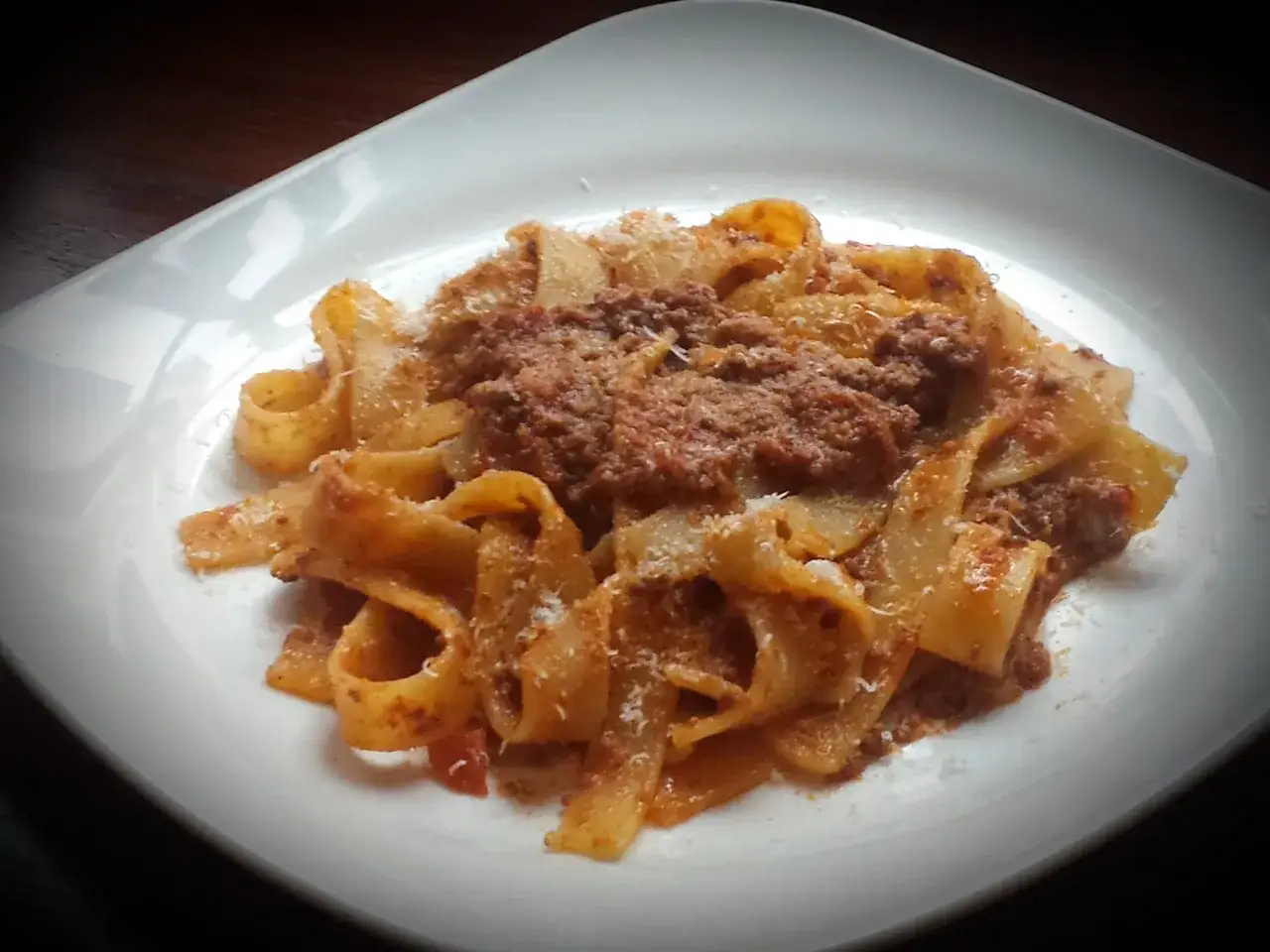 Pappardelle al cinghiale, un piatto ricco e saporito, servito su un piatto bianco.