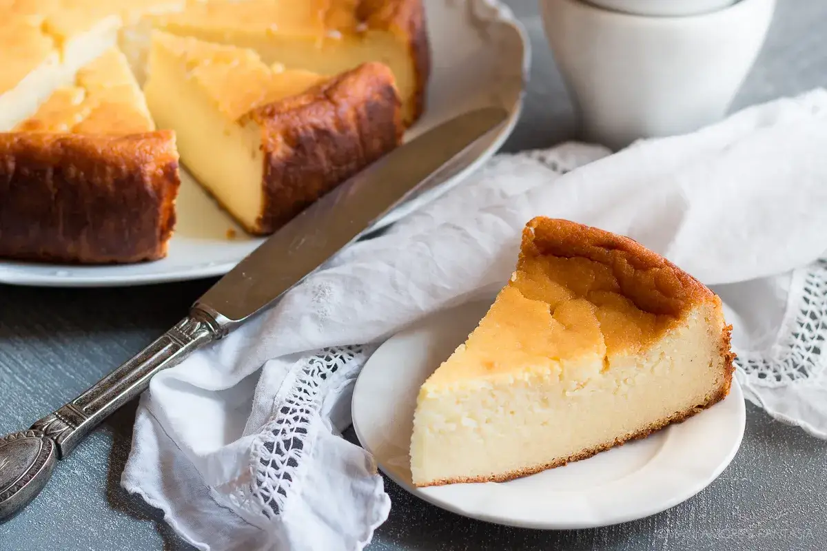 Una fetta di migliaccio napoletano ricetta della nonna, dorato e soffice, su un piattino bianco.