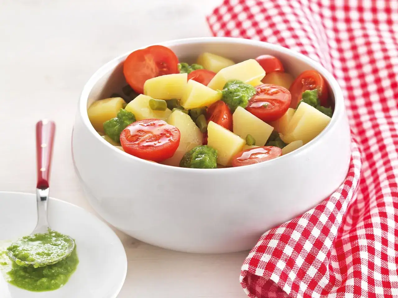 Una fresca insalata di patate estiva con pomodorini e piselli, condita con una salsa verde vibrante.