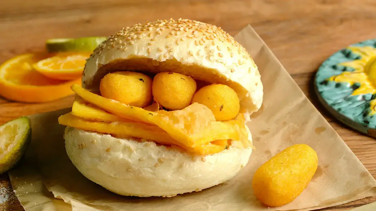 Pane e panelle, un panino morbido con panelle fritte e croccanti, accompagnato da spicchi d'arancia e limone.