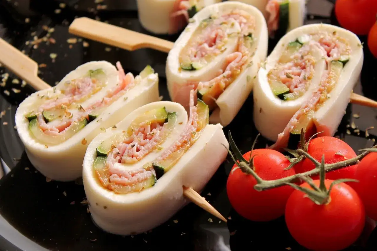 Sfoglia di mozzarella come riempirla: rotolini con prosciutto, zucchine e spezie, serviti con pomodorini.