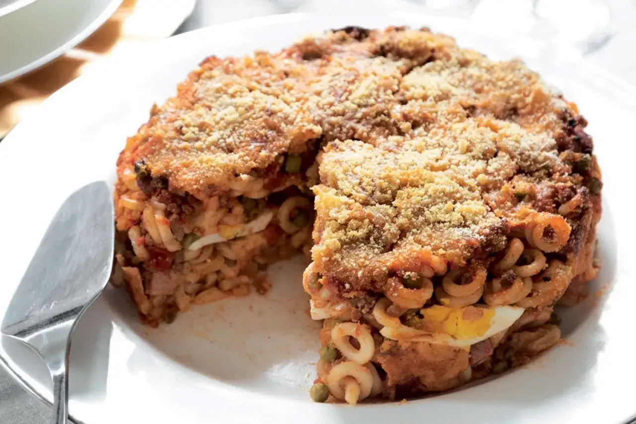Anelletti alla siciliana, un tortino di pasta al forno con ragù, piselli, uova sode e formaggio, dorato e croccante.
