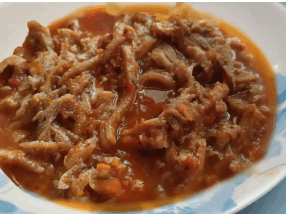 Un piatto fumante di trippa alla parmigiana, con la trippa morbida immersa in un ricco sugo di pomodoro e spezie.