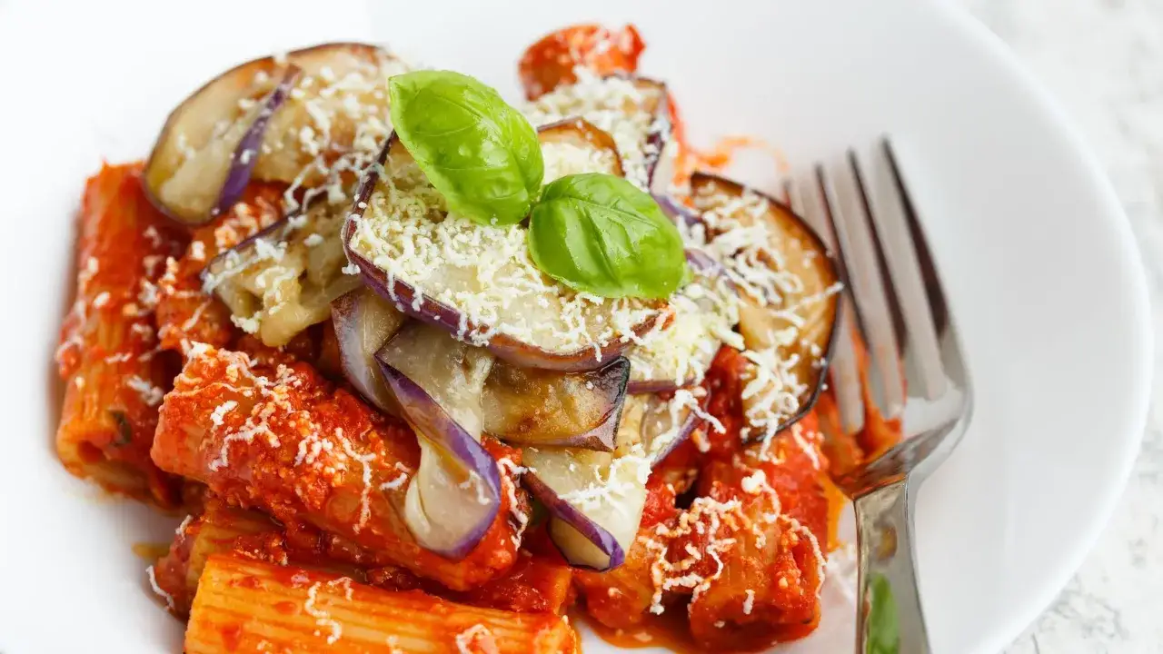 Pasta alla Norma, la ricetta della nonna: rigatoni conditi con sugo di pomodoro, melanzane fritte, ricotta salata e basilico fresco.