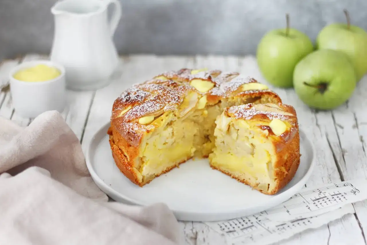 Una deliziosa torta di mele con crema pasticcera, cosparsa di zucchero a velo, pronta per essere gustata.