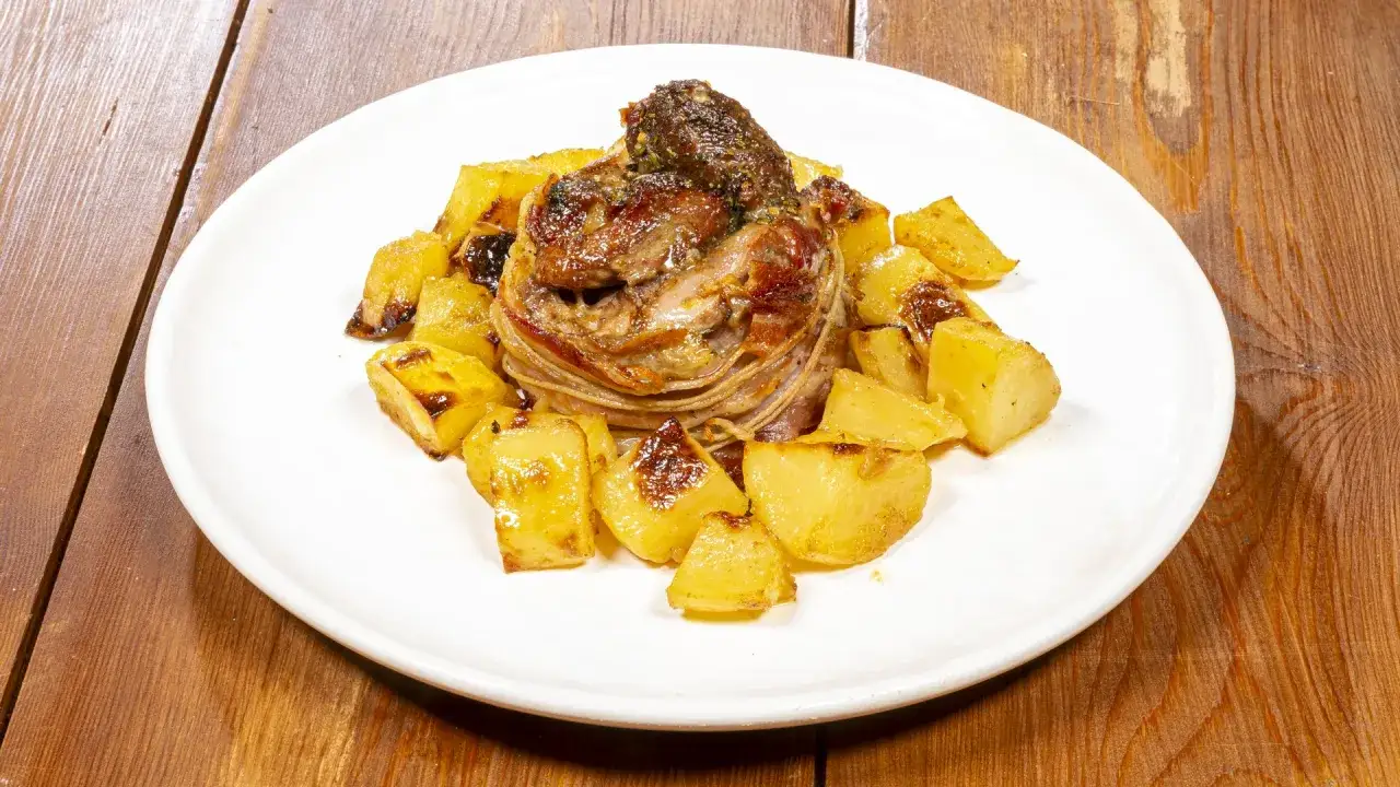 Un succulento agnello al forno con patate dorate, un piatto che profuma di tradizione e sapori autentici.