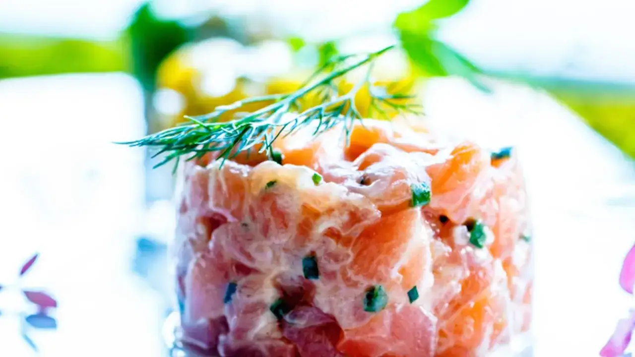 Deliziosa tartare di salmone fresca, guarnita con aneto e erba cipollina, pronta per essere gustata.