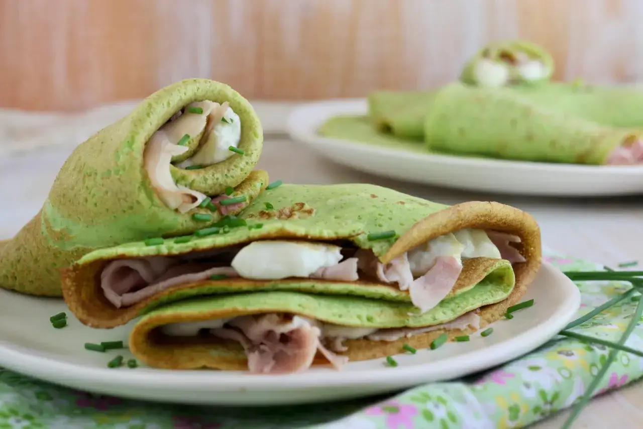 Deliziose crepes di zucchine ripiene di prosciutto e formaggio, guarnite con erba cipollina.