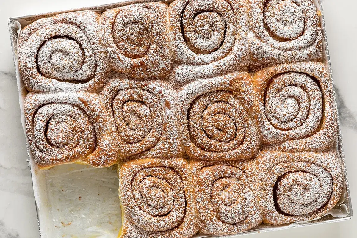 Rotolini alla cannella appena sfornati, cosparsi di zucchero a velo. Perfetti dolci da fare in casa per una colazione speciale.