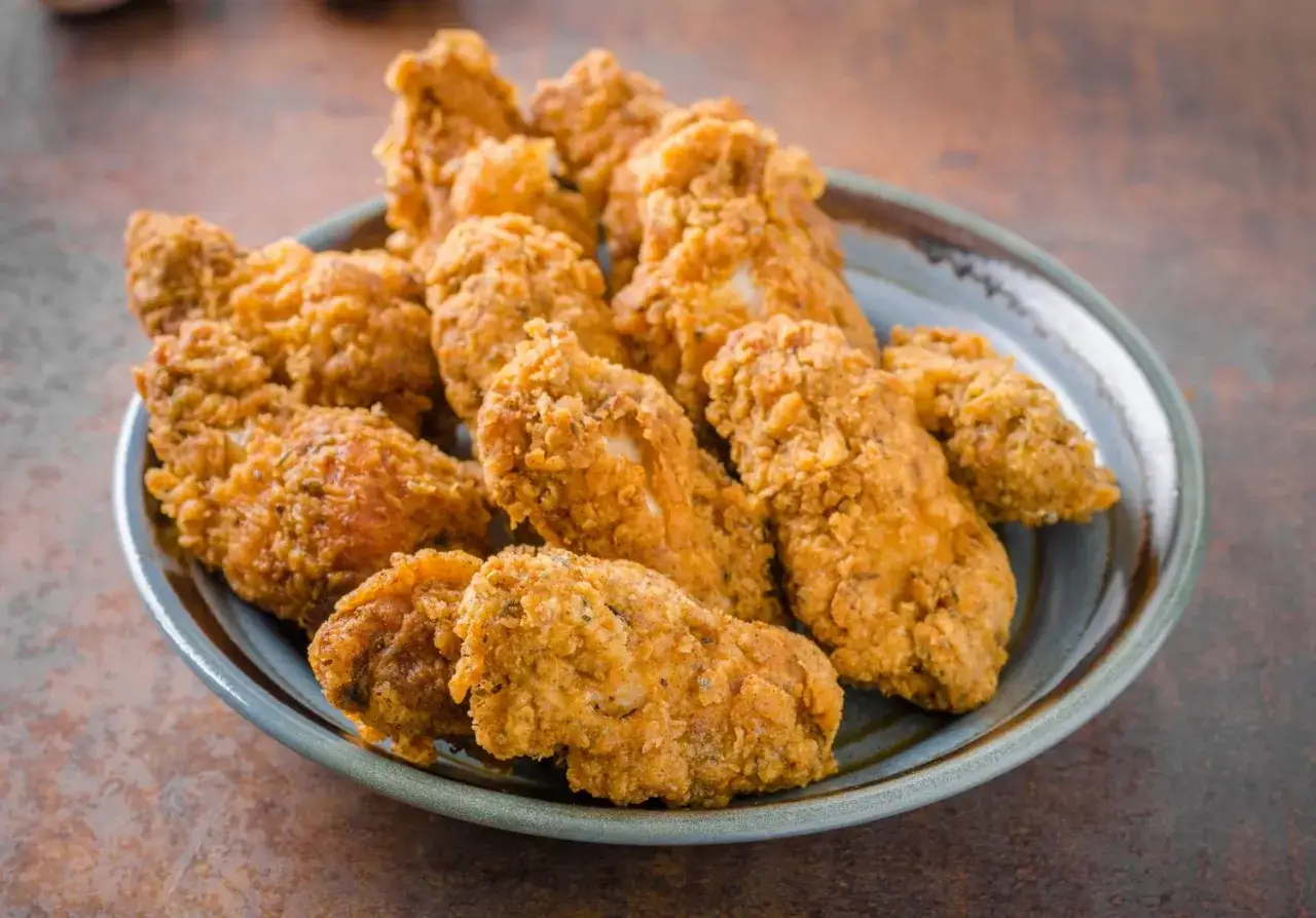 Piatto colmo di alette di pollo fritte, dorate e croccanti, pronte per essere gustate.