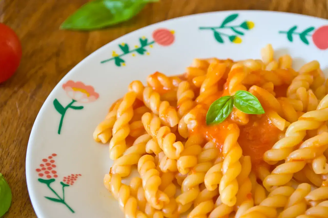 Un piatto di pasta con pomodorini e basilico fresco, servito su un piatto decorato con fiori.