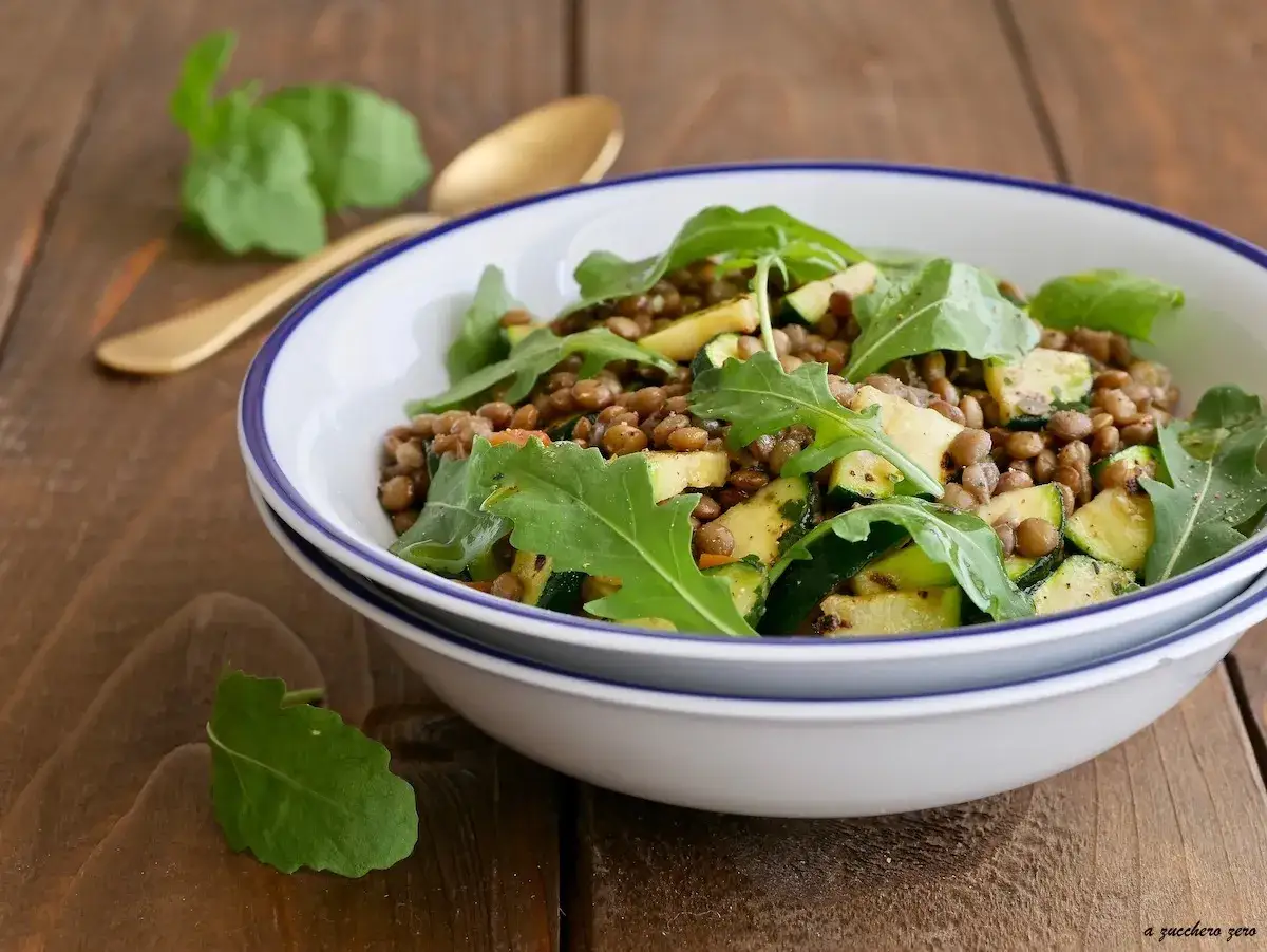 Deliziosa insalata di lenticchie con zucchine e rucola, guarnita con un cucchiaio dorato.