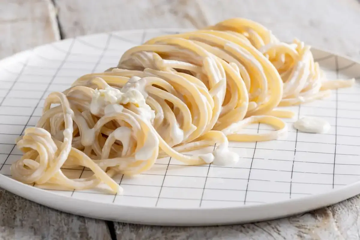 Un piatto di spaghetti in bianco cremosi, conditi con una salsa leggera e qualche fiocco di formaggio.
