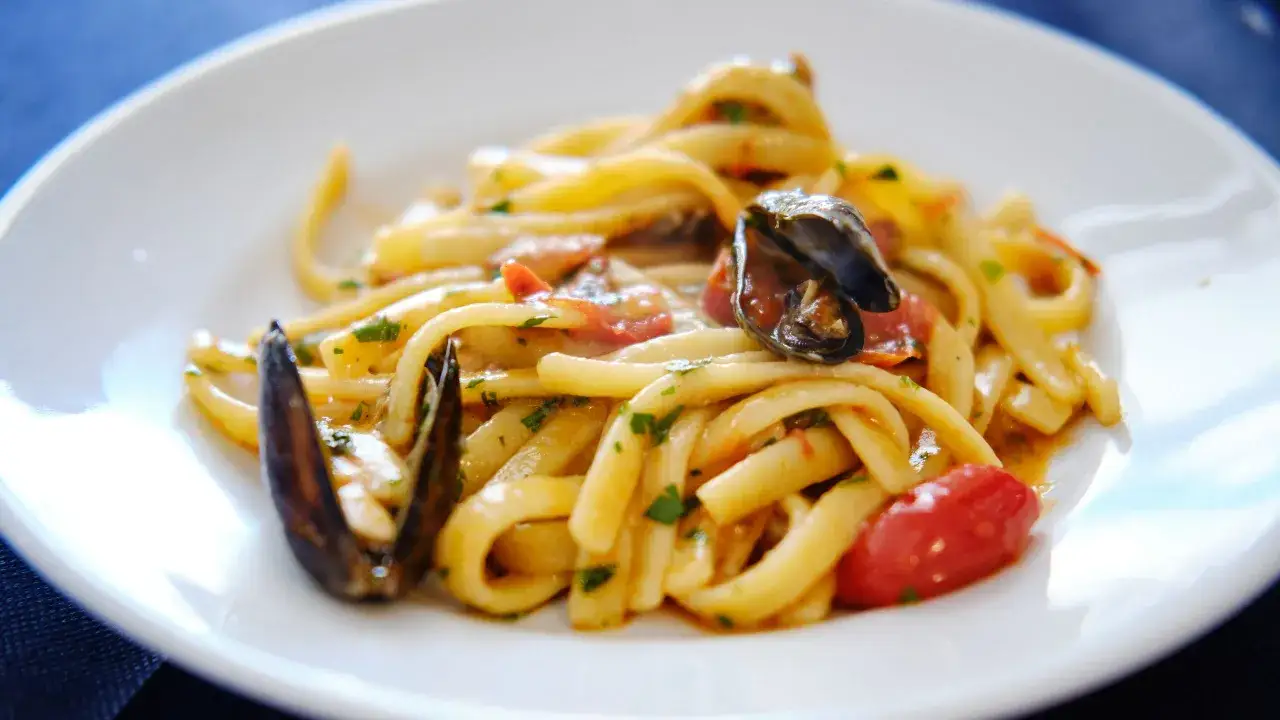 Un piatto invitante di scialatielli ai frutti di mare, con cozze, pomodorini e prezzemolo fresco.