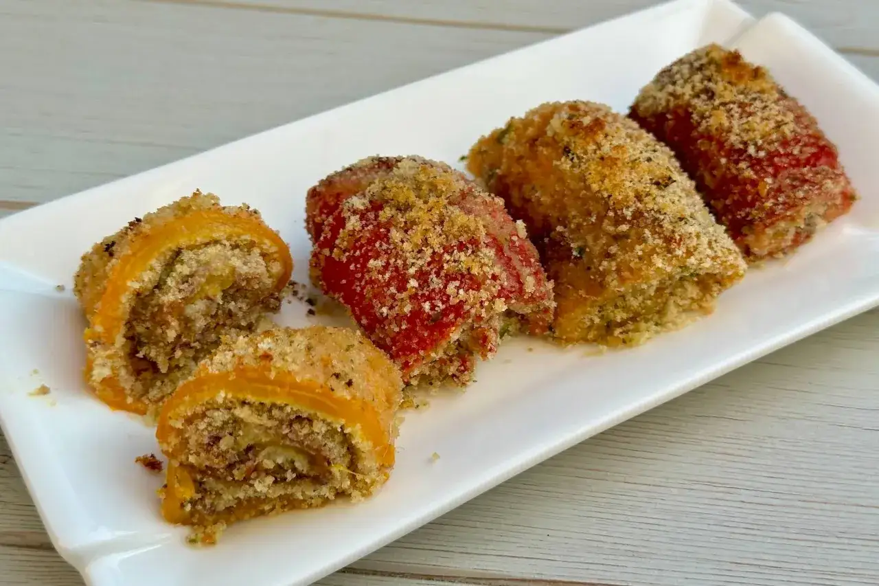 Involtini di peperoni ripieni e impanati, serviti su un piatto bianco.