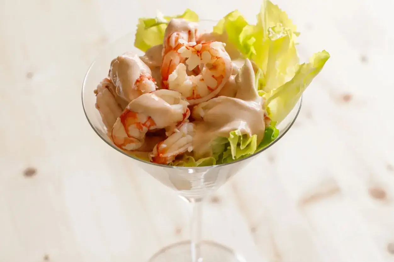 Gamberetti in salsa rosa, un antipasto fresco e gustoso servito in una coppa di vetro con foglie di lattuga croccante.