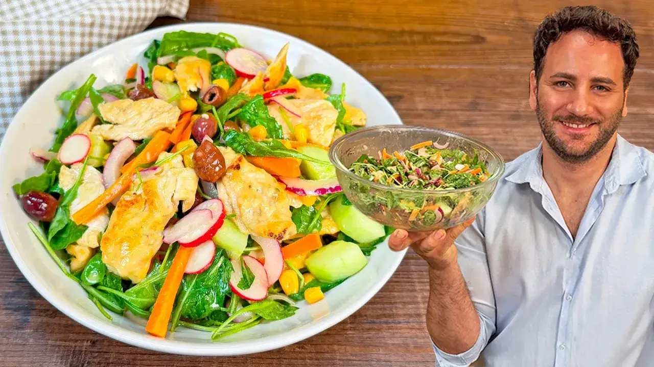 Un uomo sorridente mostra una grande insalata di pollo colorata con verdure fresche, mais e olive.