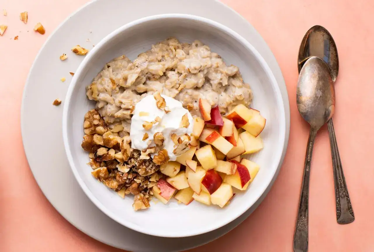 Porridge cremoso, perfetto per una colazione sana. Questa porridge ricetta 1 persona include mele a cubetti, noci croccanti e una cucchiaiata di yogurt.