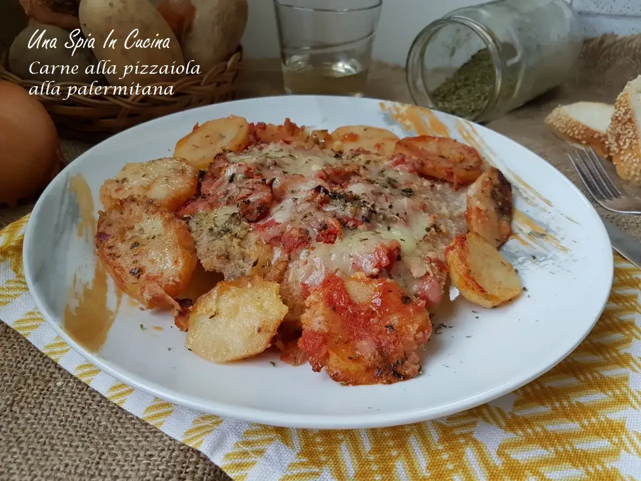 Piatto di carne alla pizzaiola siciliana con patate dorate, pomodoro e formaggio fuso.