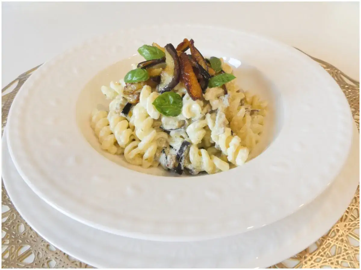 Fusilli con melanzane in bianco cremosa, guarniti con basilico fresco. Un piatto invitante e saporito.
