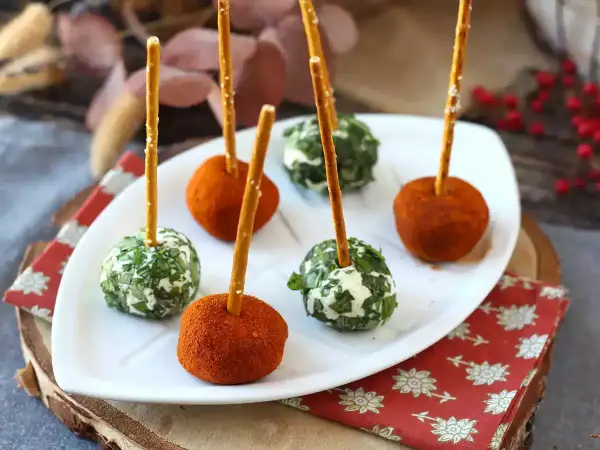 Sfere di ricotta al forno, alcune ricoperte di erbe fresche, altre di paprika, infilzate con grissini.